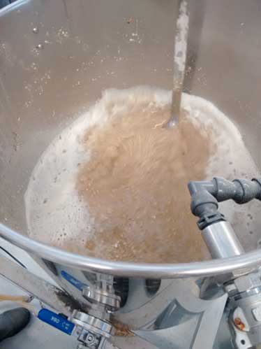 Adding all the grains to hot water, allowing to the starches in the grain to convert to fermentable sugars.